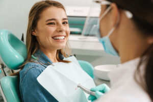 European young woman smiling while sitting in medical chair at dental clinic